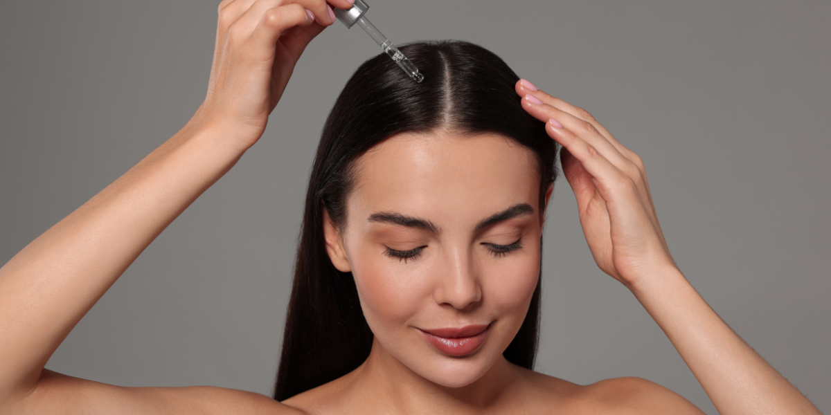 Woman using applicator to apply hair serum to the roots of her hair.