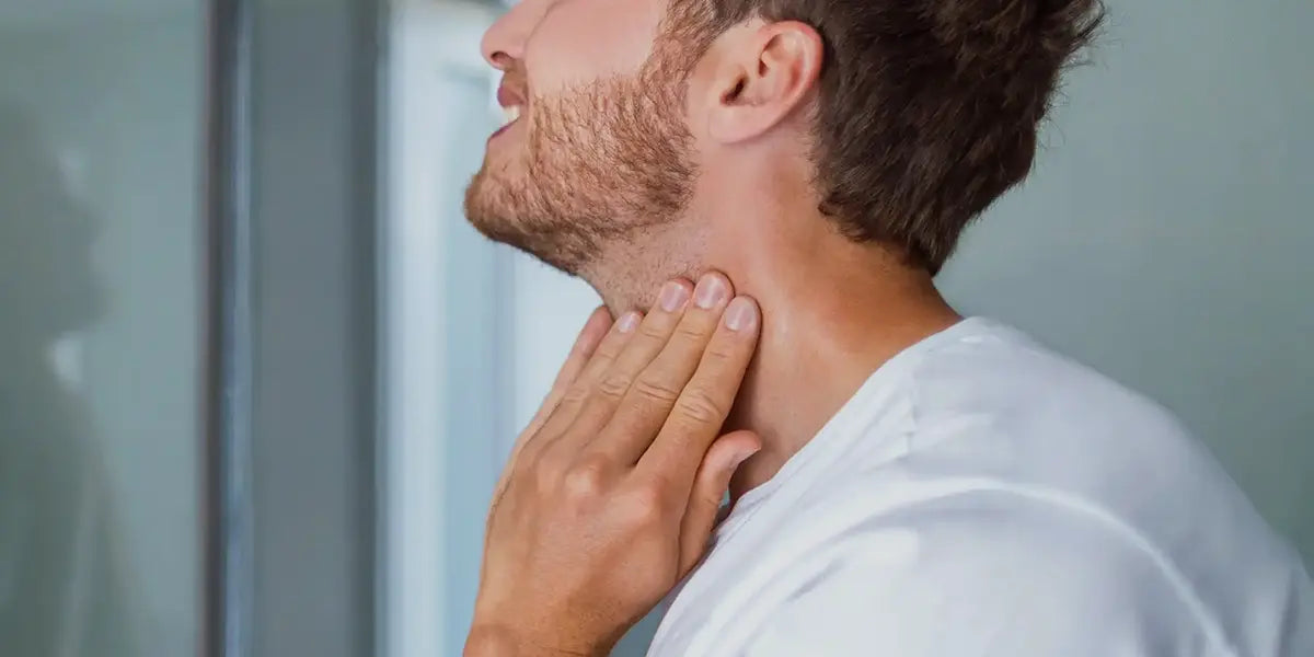 Man touching thyroid gland for signs of hypothyroidism leading to hair loss.