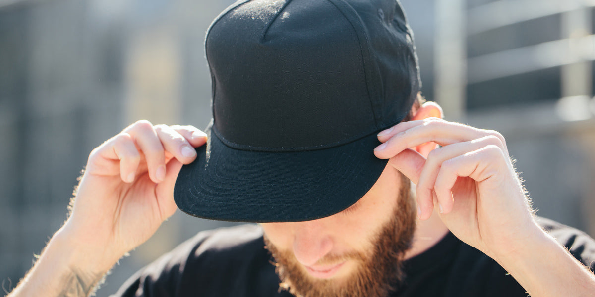 Young man wearing hat to hide hair loss.