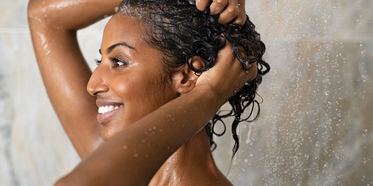 Image of woman using conditioner on her hair in the shower.