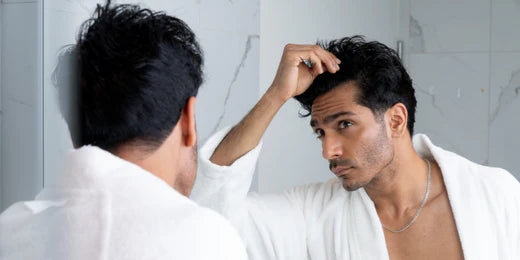 Man looking at his hairline in the mirror.