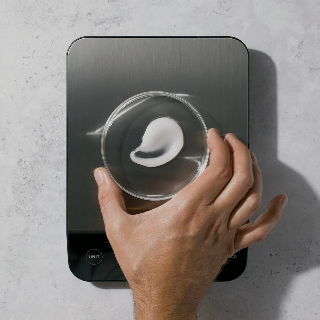 a hand measuring out a custom hair loss solution from xyon