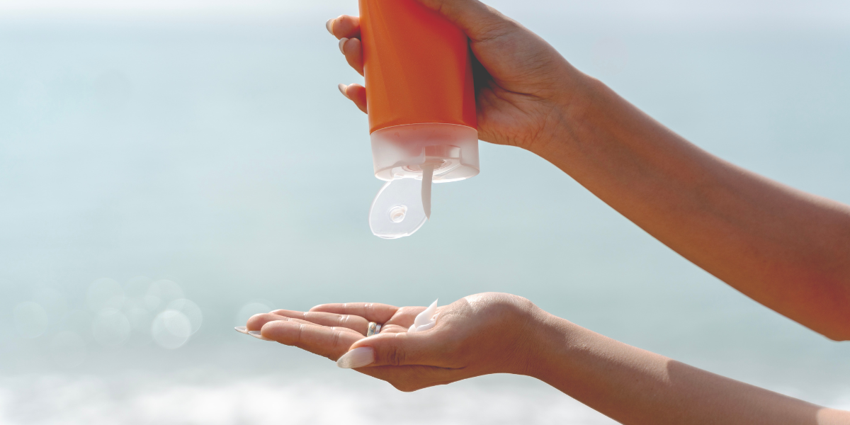 Image of sunscreen bottle being squirted onto the palm of a hand.