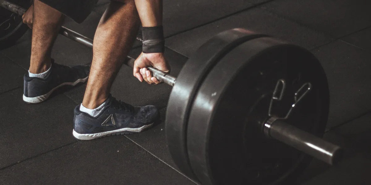 Man leaning down to lift weights to build muscle after using finasteride use.