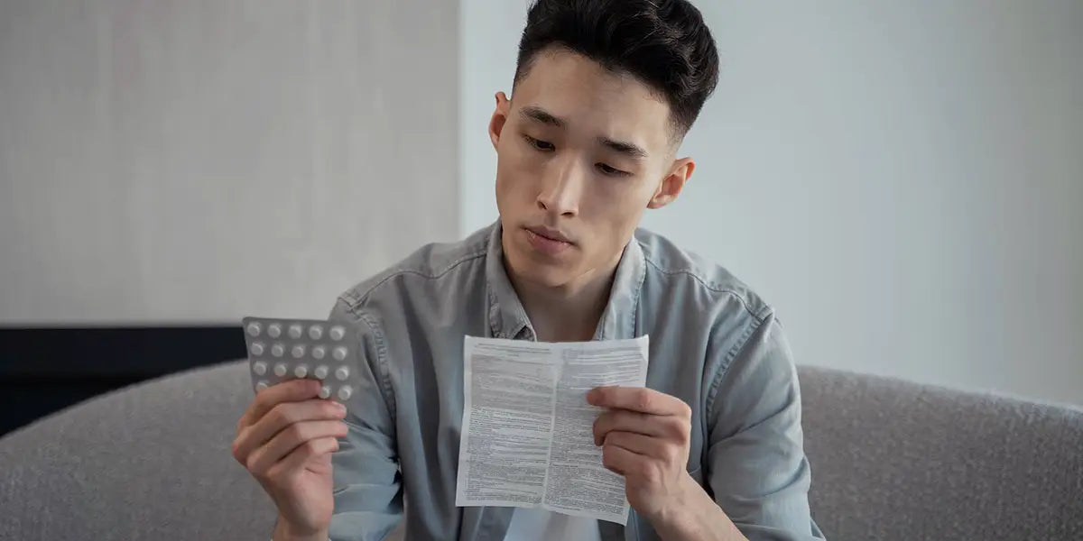 Man examining drug brochure for finasteride interactions.