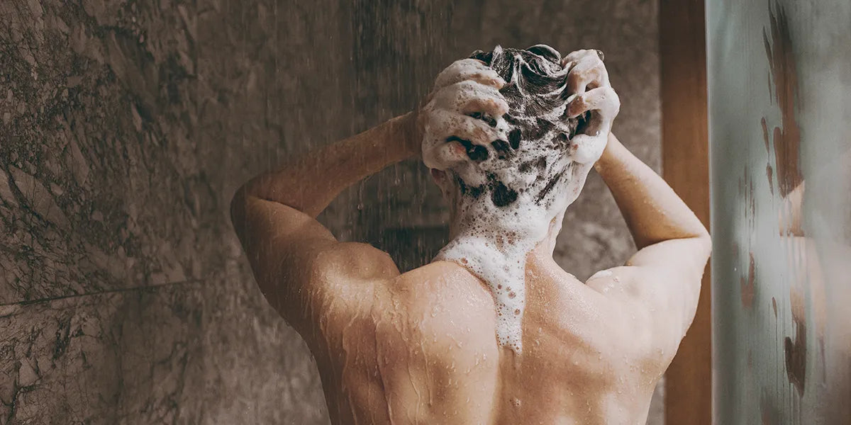 Man in shower using saw palmetto shampoo to help with hair loss.