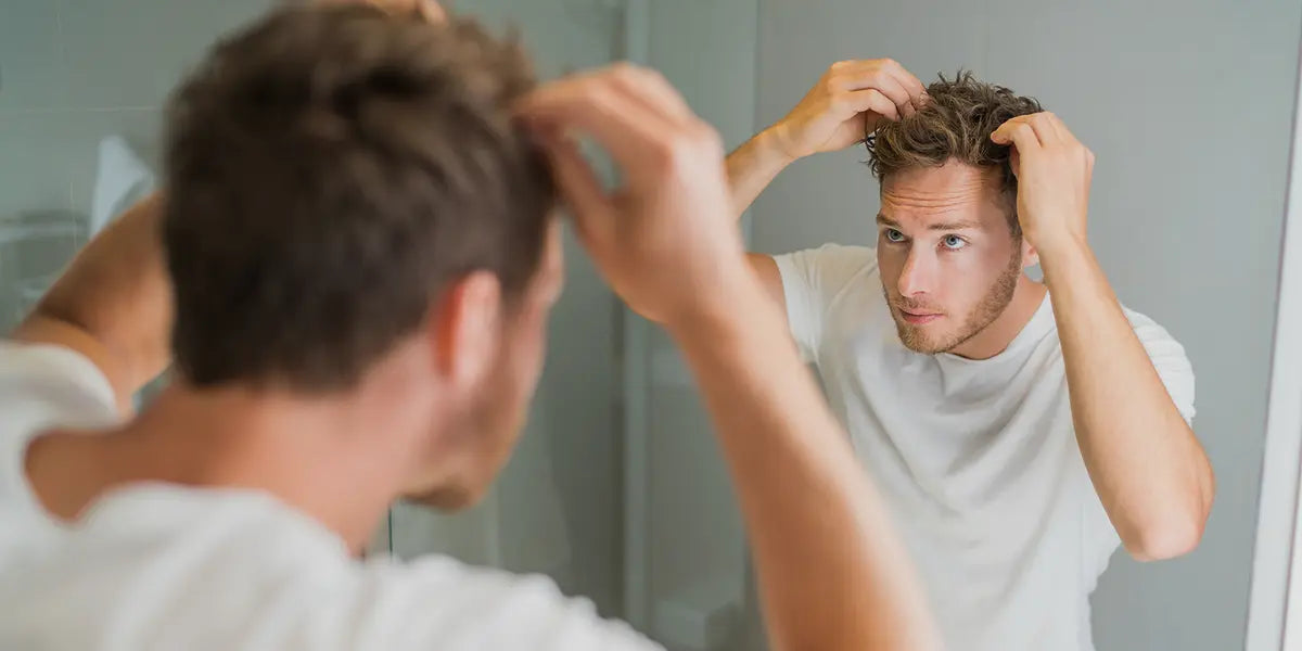 Man looking at hair considering using finasteride for hair loss.