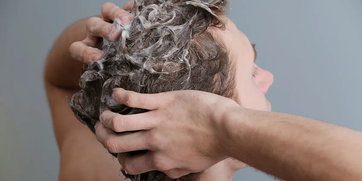 Man shampooing his hair demonstrating how to practice optimal scalp health.
