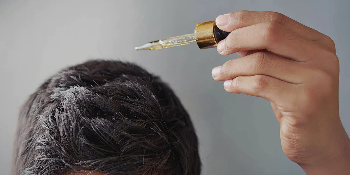 Man with dropper of rosemary oil comparing rosemary vs minoxidil effects on hair.