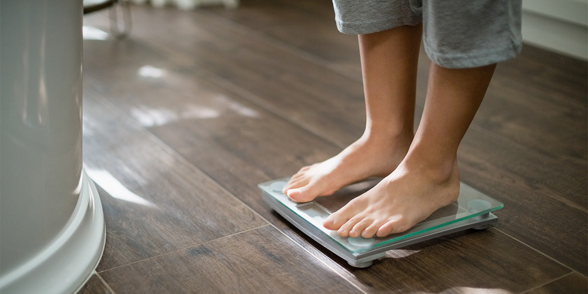 Person standing on scale measuring weight gain due to spironolactone.