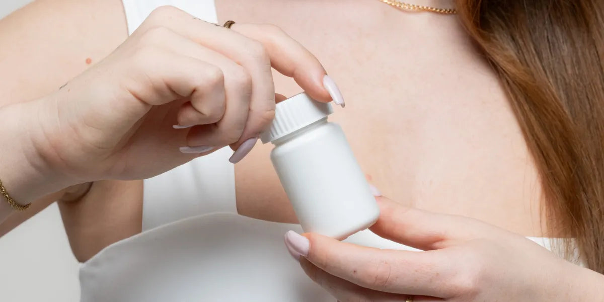 Closeup of woman holding bottle of minoxidil tablets.