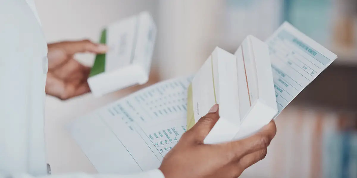 Woman holding spironolactone side effects safety leaflet and medication boxes.