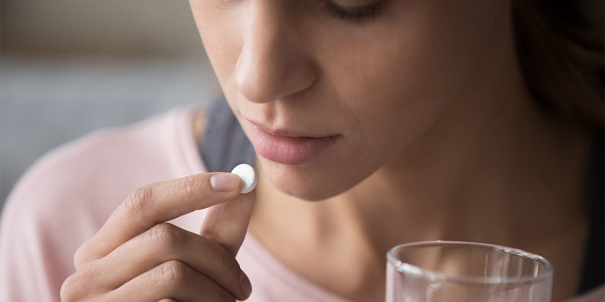 Young woman taking a vitamin D tablet for hair loss.