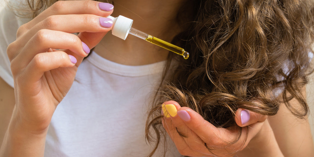 Woman applying hair oil to her hair.