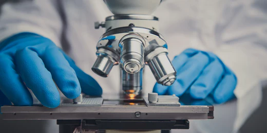 Scientist examining slides under microscope to gather data on XYON Health clinical studies.